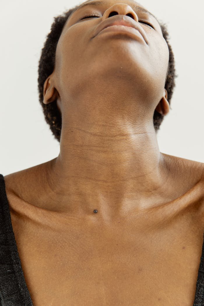 Close-up portrait showcasing a relaxed posture of a woman with her head tilted back, emphasizing skin texture.
